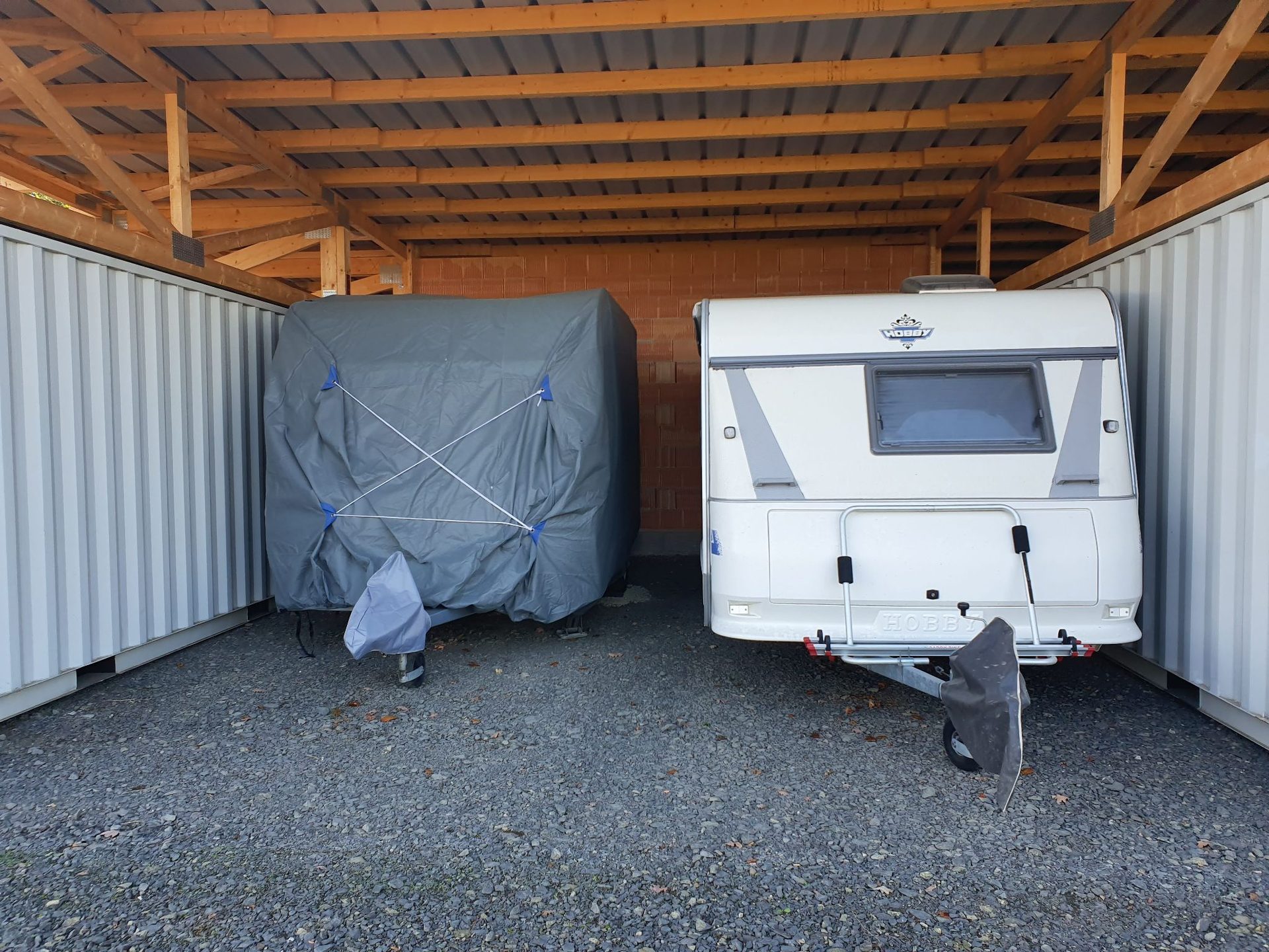 Carport mit abgedecktem und offenem Wohnwagen