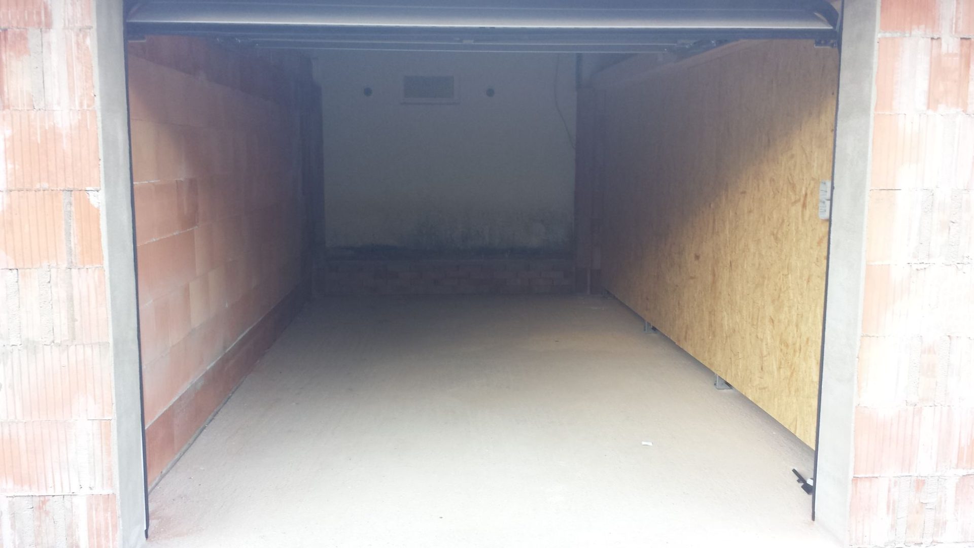Blick in eine leere Garage mit gemauerten Wänden